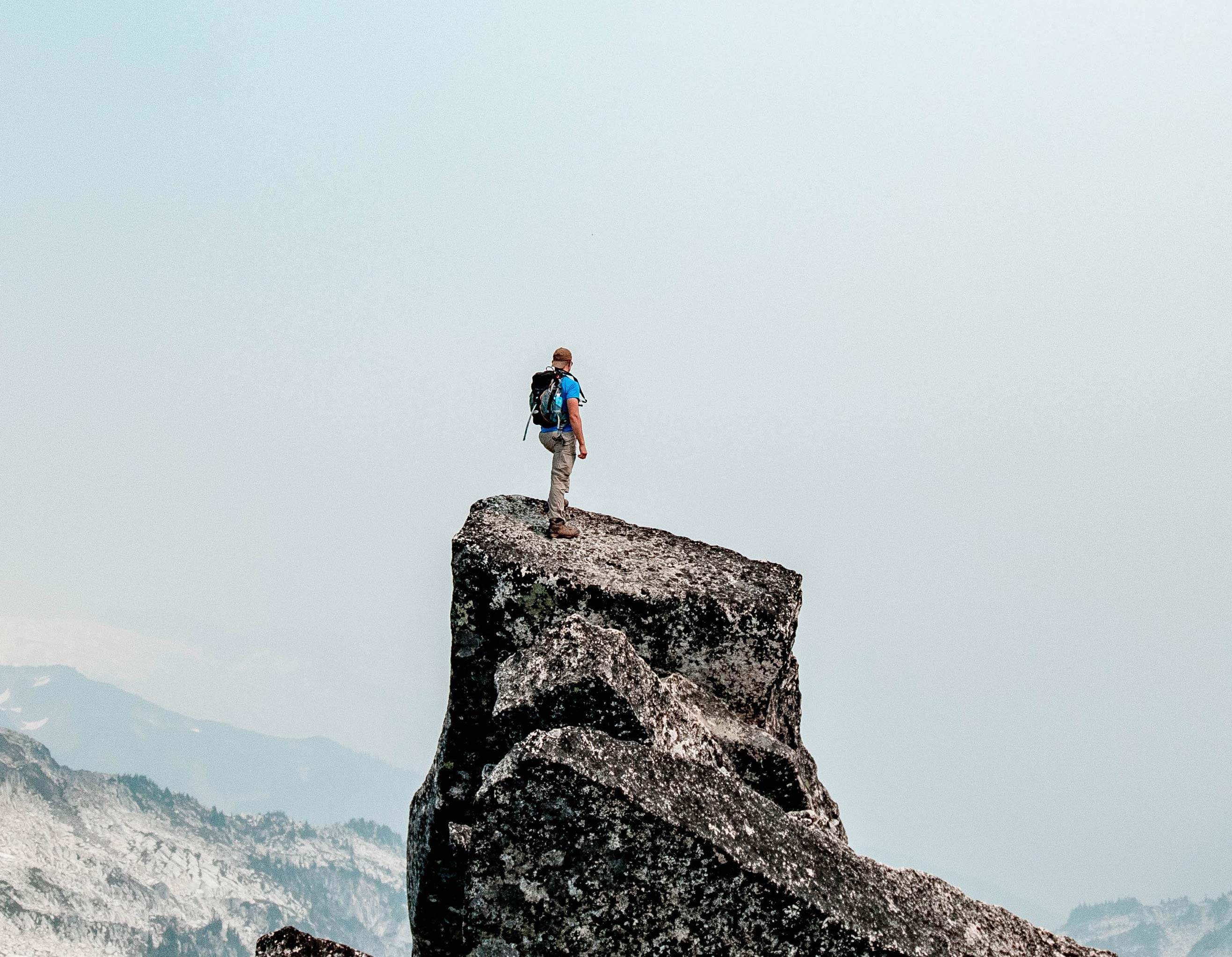 Mountain climber standing at the peak of a mountain.